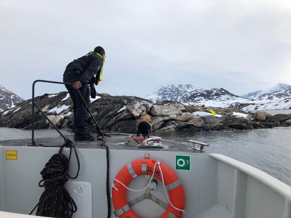 Aqqalu gør klar til at hoppe i land på øen, for at tilse 'personen' der ligger på fjeldet.