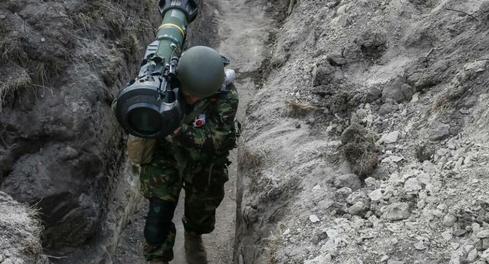 En ukrainsk soldat i en skyttegrav ved frontlinjen i det nordlige Kyiv. Han bærer på et våben, der kan sætte kampvogne ud af spillet.