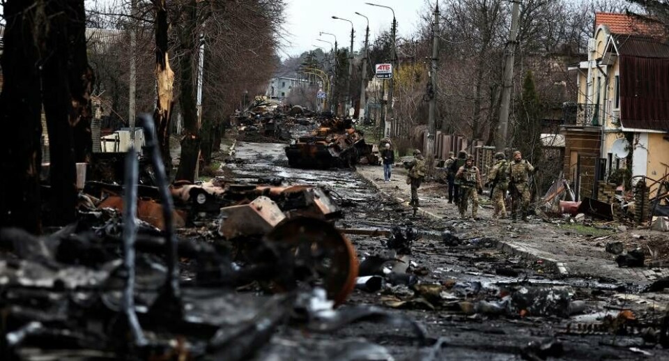 Soldater går forbi en ødelagt russisk kampvogn og pansrede køretøjer i Butja. Butja er angiveligt nu tilbage på ukrainske hænder.