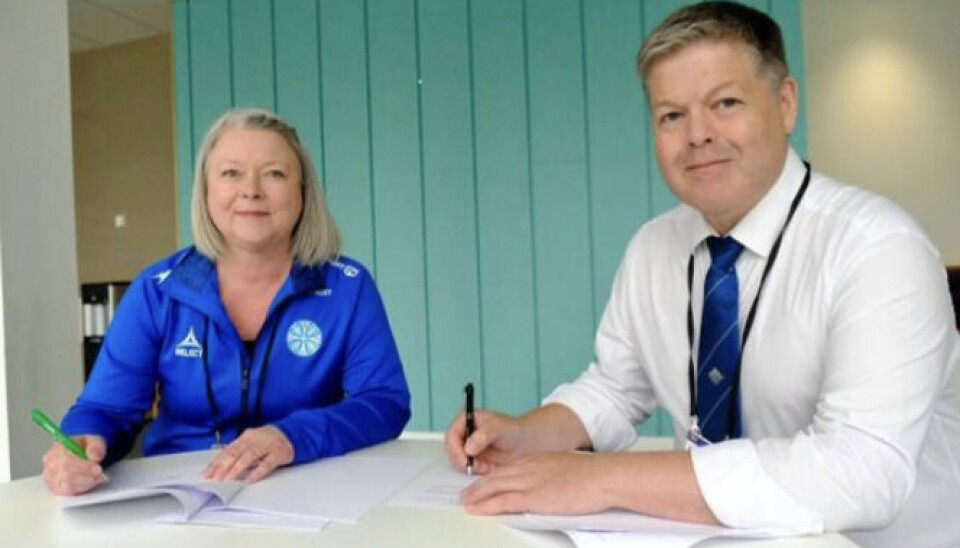 Færøske Elin Heðinsdóttir Joensen underskriver her aftalen om værtsskabet for Island Games I 2027. Hun ses sammen med Island Games-formanden Andrew Inkster.