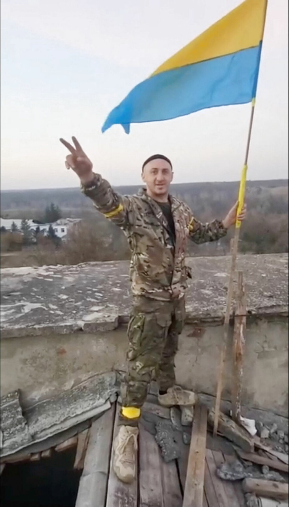 En mand i militæruniform hejser et ukrainsk flag i Kherson-regionen i det sydlige Ukraine.