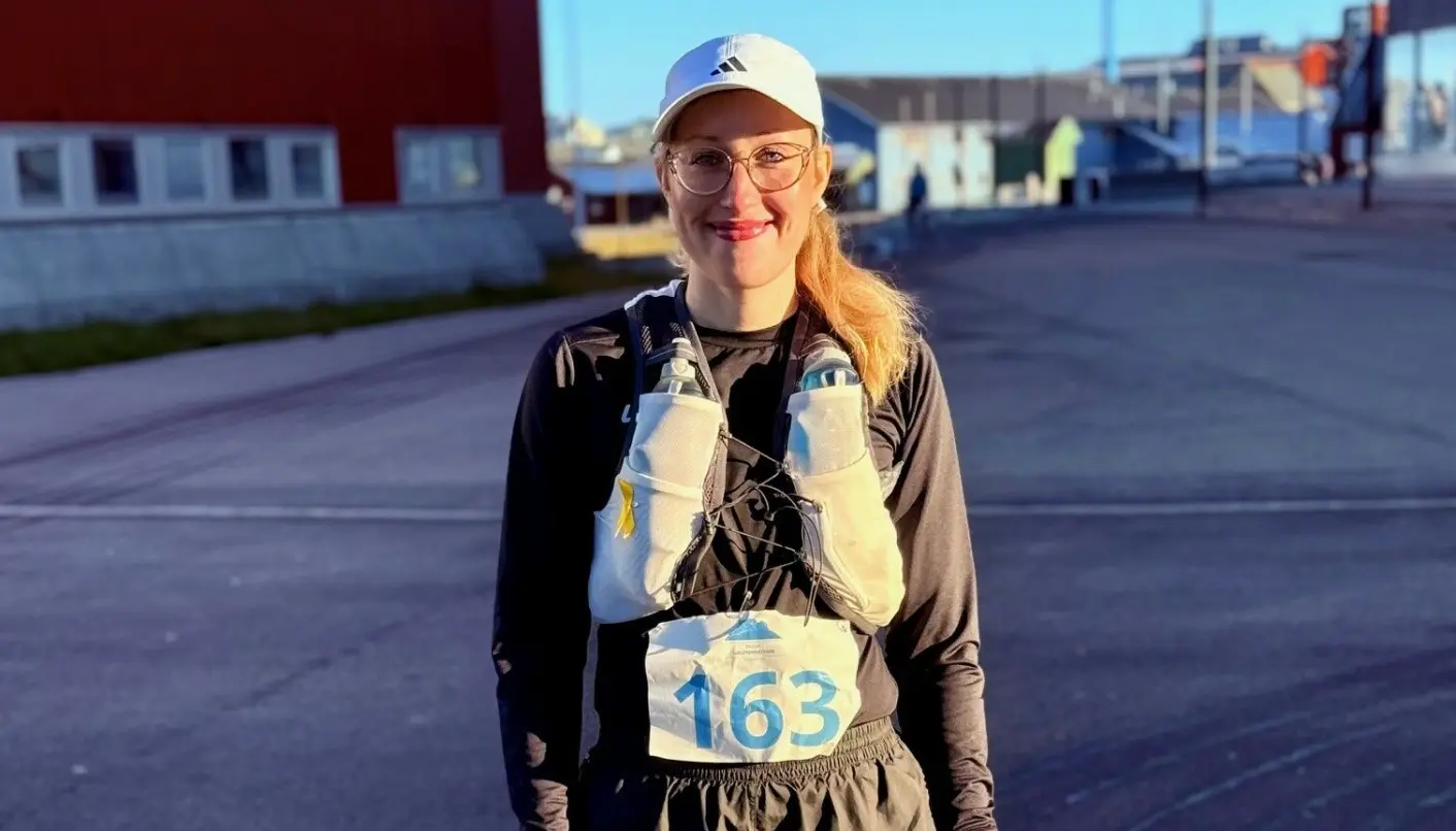 Charlotte Bengstrøm smiles before the start – ready to test both will and knees over 21.1 kilometers in Nuuk's late summer sun.
