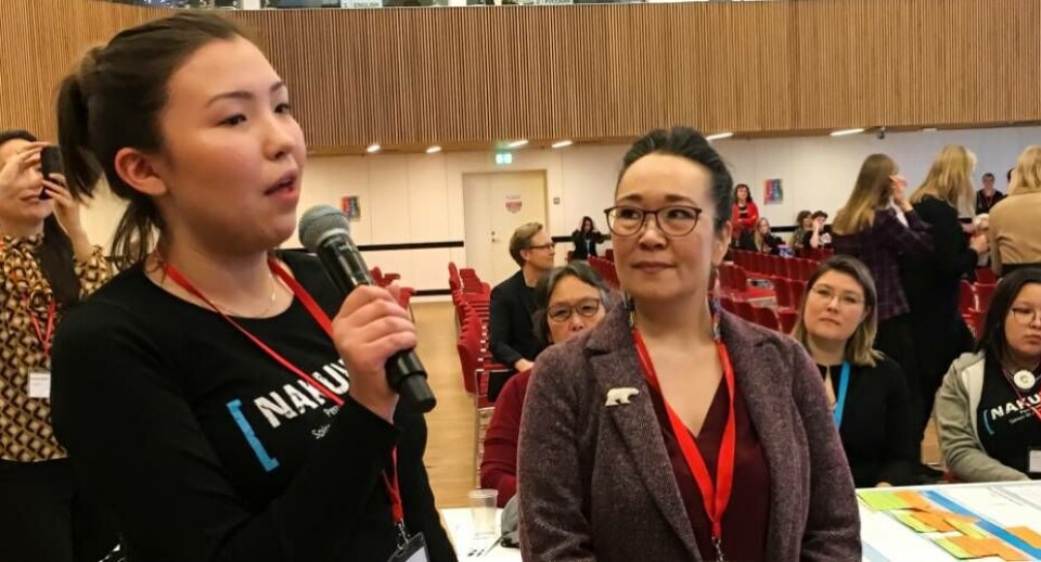 Nivi Rosing fremlægger planen for forsamlingen mens Aviâja Egede Lynge yder moralsk støtte