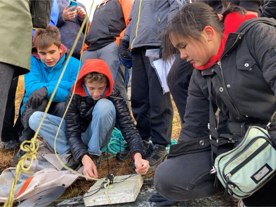 Eleverne fra Nuuk International Friskole arbejder sammen om at sætte en tidevandsmåler godt fast inden sten og måler smides i havet og målingerne kan begynde.