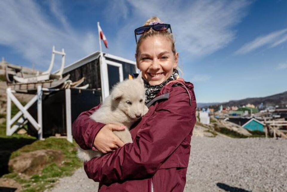 Mille Gori holder på en hundehvalp. Julekalenderen 'På eventyr i vilde Grønland' skal ses i skolebænken.