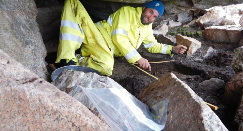 Kristoffer Dahle udgraver under trange kår et prøvehul i det fremtøede klippely. Mindst tre barklagte gulvlag og enkelte knogler dukkede frem af hullet.