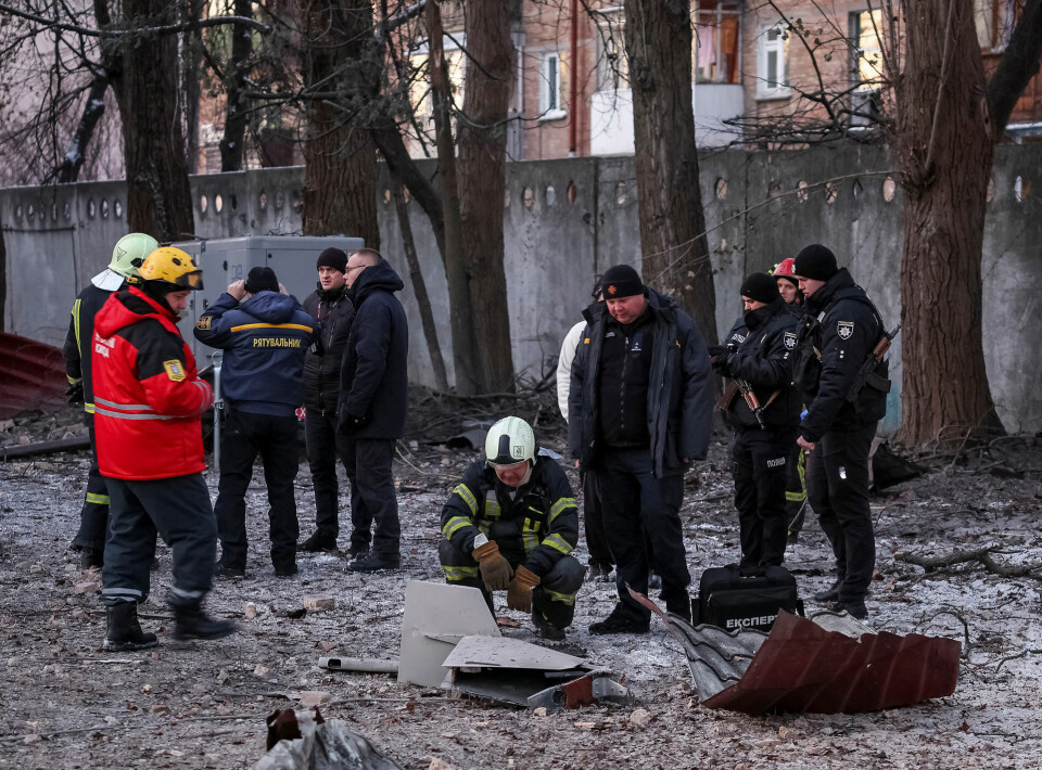 Redningsfolk og politibetjente undersøger dele af en drone ved en bygning, der blev ødelagt af et russisk droneangreb onsdag morgen.