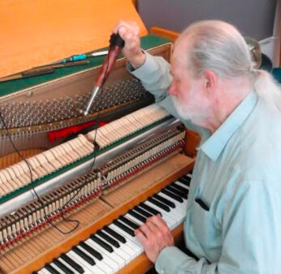 Jim Milne ses her, mens han er i gang med at stemme musikskolens eneste akustiske klaver.