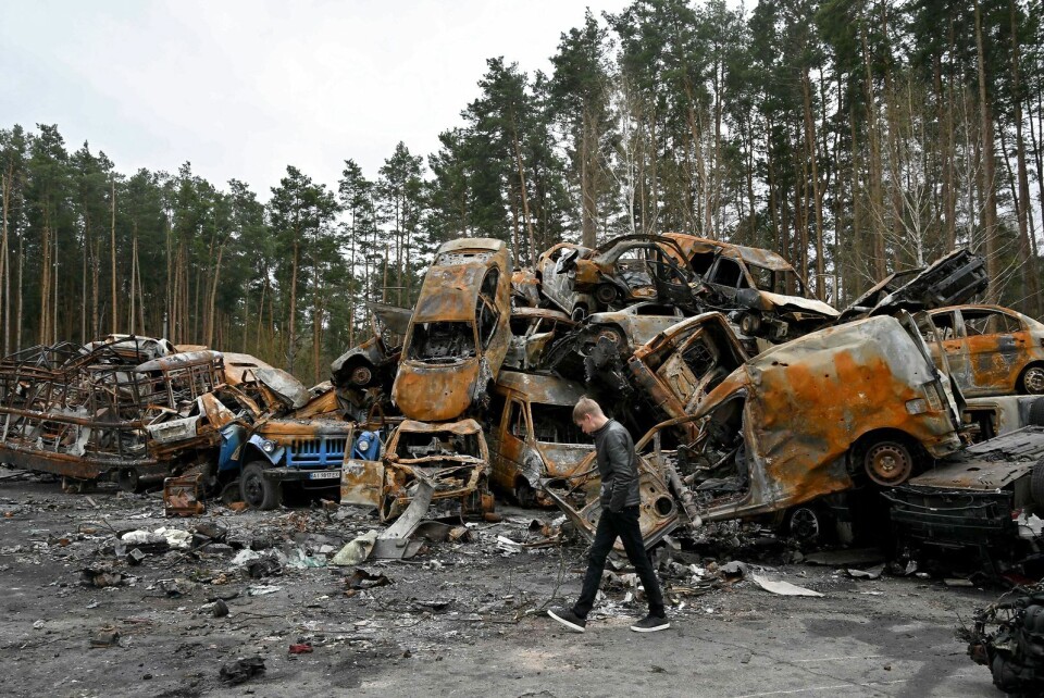 En mand går forbi ødelagte og brændte biler i Irpin den 19. april 2022 under den russiske invasion af Ukraine. Krigen ventes at præge verdensøkonomien.