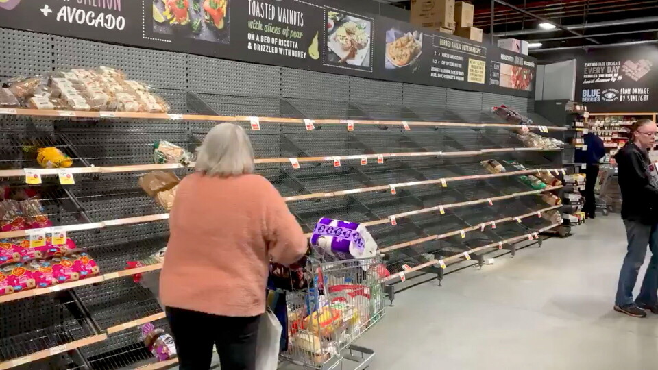 En kvinde skubber en indkøbsvogn forbi næsten tomme hylder i Casey Market Town i Canberra, Hovedstaden er under nedlukning, og myndighederne har appelleret til folk om ikke at hamstre varer.