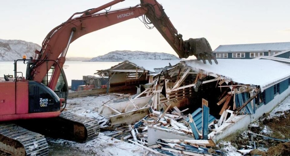 Nedrivningen går rimeligt hurtigt. Hvor der i gamle dage gik mange folk i dagevis med hammer og koben, bliver det hele klaret på under en arbejdsdag ved hjælp af en gravko og masser af rå kraft. Foto: John Rasmussen, Narsaq Foto