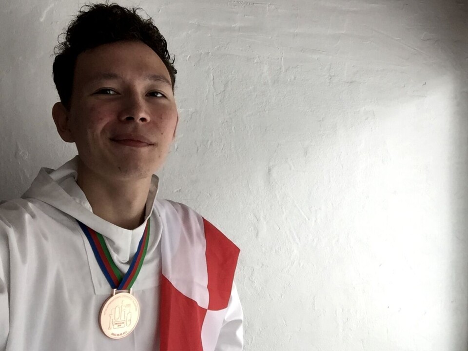 Laurids Abelsen Holm i hvid anorak med den grønlandske flag og bronzemedalje rundt om halsen Laurids A. Holm